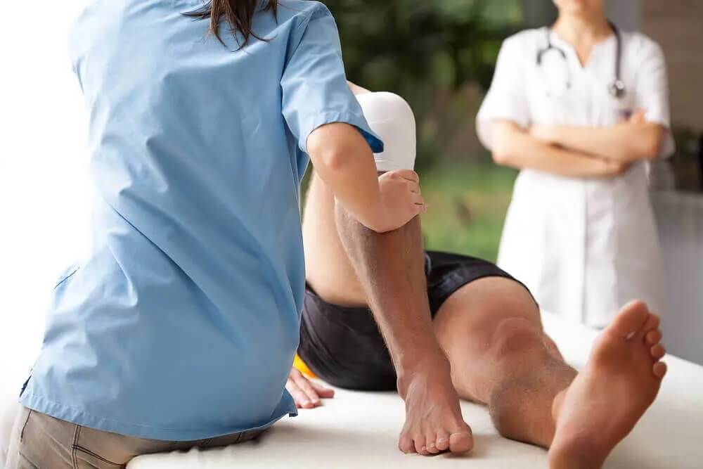 Female chiropractor treating injured knee